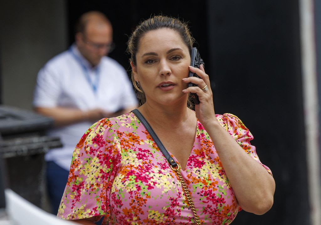 Kelly Brook on phone wearing pink dress leaving Global Radio