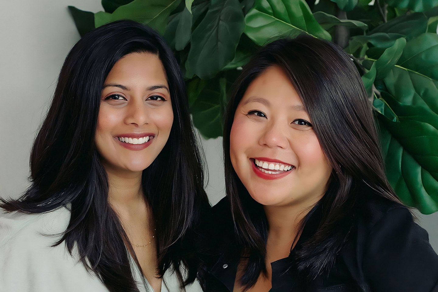 two women in business professional attire smiling