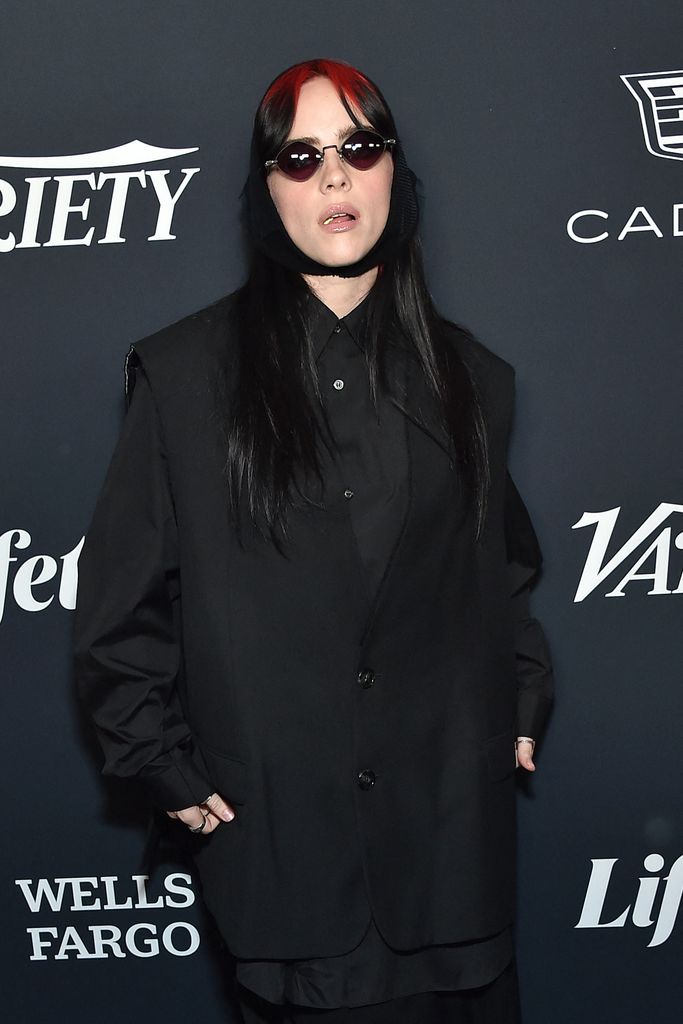 Billie Eilish in black blazer and shirt and red sunglasses